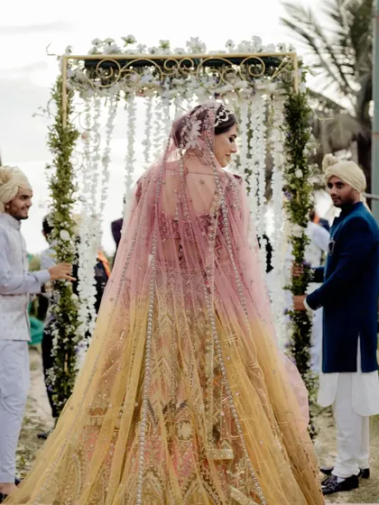 A bride's grand entrance under a canopy of white flowers, showcasing a beautiful start to the wedding ceremony.