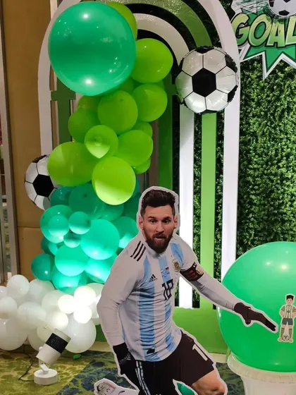 A close-up of the Messi cutout and the green balloon garland, key elements of the football party decor.