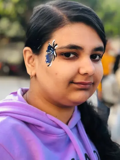 A dark blue butterfly with white spots, creating a beautiful night-sky effect on the face.