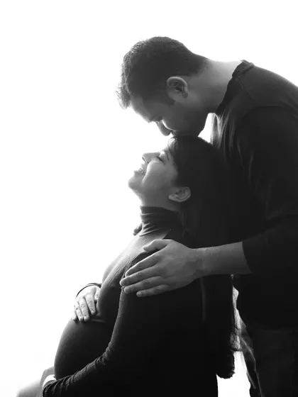 A tender black and white portrait of a husband kissing his wife's forehead. The high-key lighting and their happy expressions make this a pure and loving image.