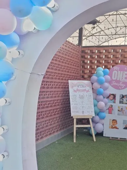The welcome area for a unicorn-themed party, featuring a milestone photo board and a balloon arch.