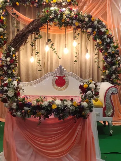 A beautiful naming ceremony setup featuring a decorated cradle (thottilu) as the centerpiece, surrounded by a rustic floral arch and soft drapery.