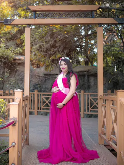 Wearing a "Mom to be" sash and a flower crown, this solo portrait is full of happiness. The flowing gown adds a touch of fairytale elegance.