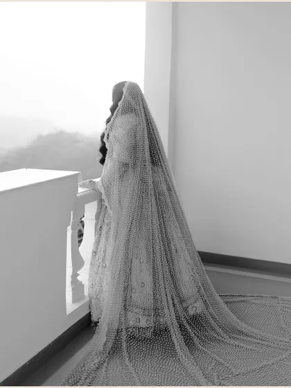 An artistic black and white shot of the bride from behind, her long, sheer veil cascading down and creating a beautiful, ethereal texture.