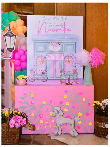 The welcome signage for the Parisian party, featuring a beautiful illustration of a French cafe, a poodle cutout, and floral details.