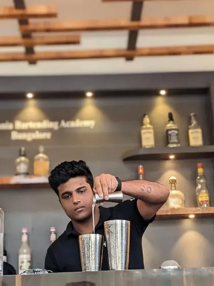 A student focuses on his pour during a practical class, learning to make gin cocktails at our Bangalore academy.
