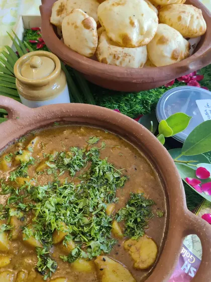 A comforting meal of fluffy puris served with a flavourful potato curry (Aloo Sabzi), presented in traditional earthen bowls for an authentic touch.