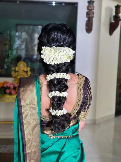This South Indian bridal hairstyle features a thick braid wrapped in fragrant jasmine flowers, or 'gajra', for a classic and timeless look.
