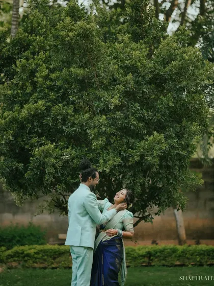 A tender moment shared between the couple during their outdoor pre-wedding shoot. The natural light and green surroundings create a soft, romantic atmosphere.