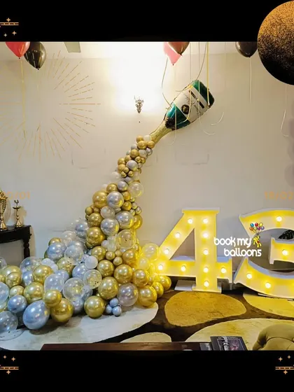 This champagne pop balloon cascade was the star of a 43rd birthday celebration. The arrangement of gold and silver balloons flowing from a champagne bottle foil balloon, paired with marquee numbers, created a festive and glamorous focal point.