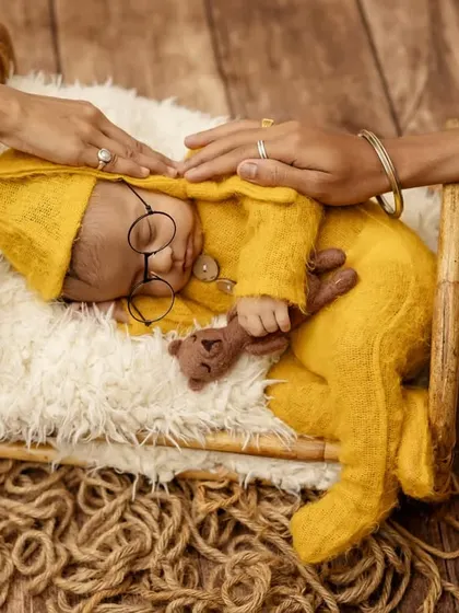 A precious moment as parents' hands gently rest on their sleeping baby during his themed newborn photoshoot.