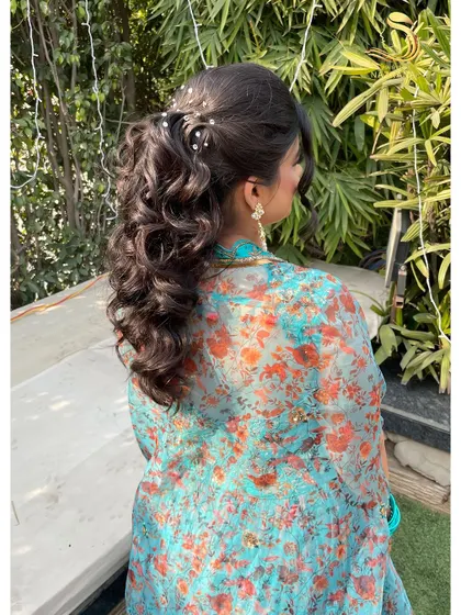 The full effect of this textured ponytail, combining volume, curls, and delicate accessories for a truly memorable hairstyle.