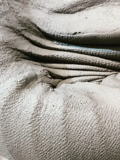 A close-up showing the texture and form of clay being worked by hand. Every piece starts with this fundamental, hands-on connection to the material.