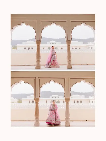 A bride in a pink lehenga stands between two arches of a palace, creating a beautifully symmetric and regal portrait.
