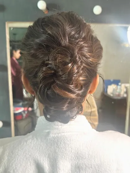 A behind the scenes look at the creation of a messy bun, showing the technique for achieving that effortless look.