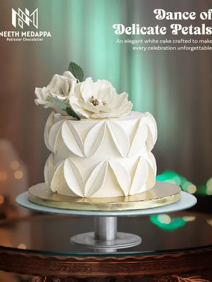 The dance of delicate petals. This elegant all-white cake features a stunning, textured petal design and is topped with handcrafted white sugar flowers.