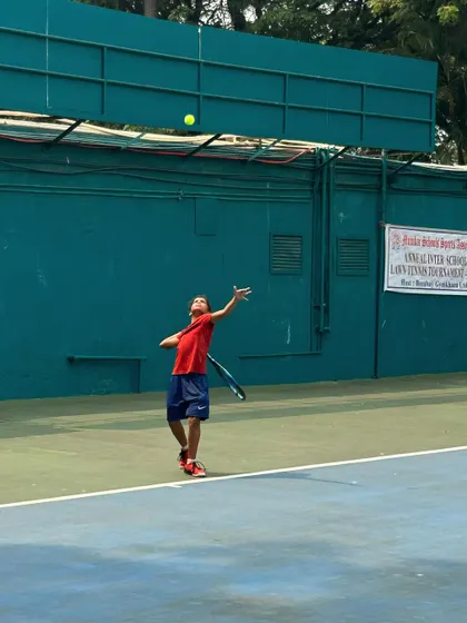A junior player tosses the ball for a serve during the MSSA finals, a moment of focus before the point begins.