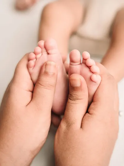 A mother's hands cradling her newborn's tiny feet, a memory to cherish forever.
