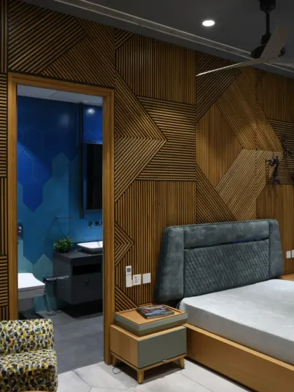 This bedroom in the Screen House features a striking zigzag-patterned veneer-clad bed back. A contrasting grey headboard balances the wooden aesthetics, adding depth and sophistication to the space.