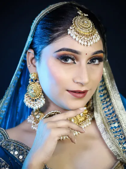 A regal bridal look in a deep blue lehenga. The cool-toned makeup with a sharp, defined eye complements the cool tones of the outfit and the silver-gold jewelry.
