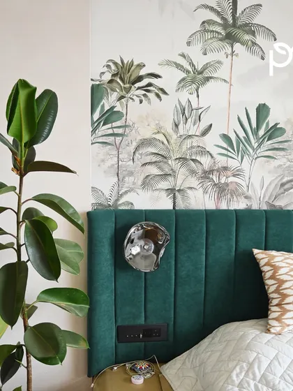 A Rubber Plant (Ficus elastica) stands next to a bed with a nature-themed wallpaper and headboard. We help clients choose houseplants that not only survive but also enhance the overall design theme of their room.