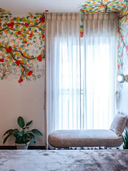 A closer look at the master bedroom mural, where the branches and leaves are painted with intricate detail. Paired with soft textures and natural light from the sheer drapes, this corner is a perfect balance of art and comfort.