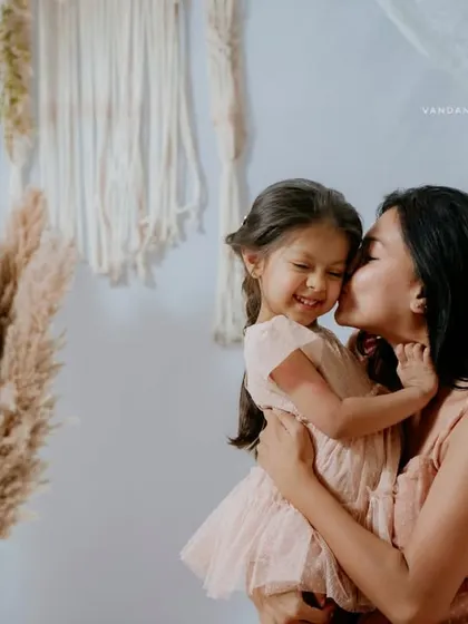 A beautiful, candid moment where the mother is kissing her smiling daughter's cheek. The genuine emotion in this shot makes it a priceless memory.