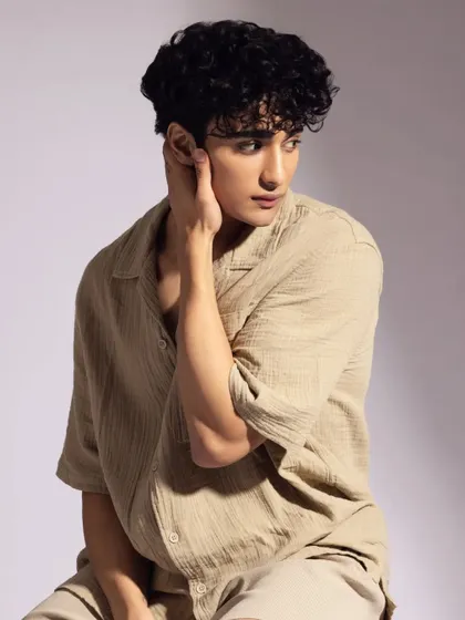 A soft, warm-lit portrait. The makeup is natural and enhances his features without being obvious.