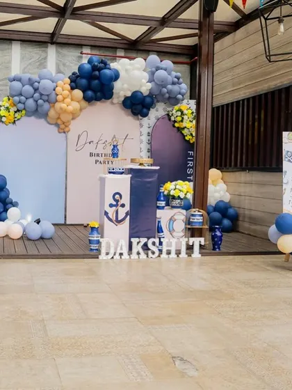 I designed this boat-themed birthday party with a nautical color scheme of navy blue and white. The setup includes an anchor prop, a personalized backdrop, and a milestone board for the birthday boy.