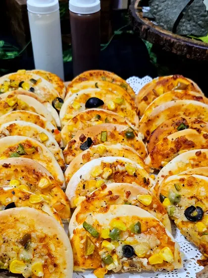 A platter of mini pizzas, neatly arranged and ready for a hi-tea party. The combination of cheese, veggies, and a soft base makes them irresistible.