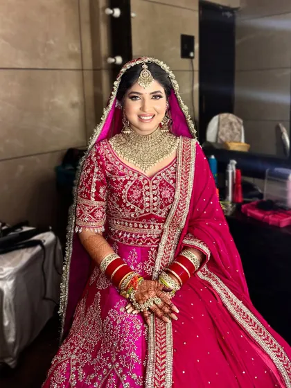 A full shot of Naina in her stunning pink wedding lehenga. The makeup is balanced to complement the bright, happy color of her outfit.