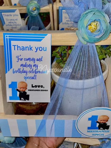 Here is a "Boss Baby" themed return gift we designed for a first birthday. The blue and white striped hamper includes a plant, a jar of goodies, and a custom thank you card featuring the birthday boy.