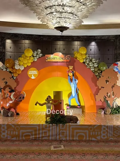 A wide shot of the complete stage, showing the scale of the backdrop, life-sized characters, and balloon garlands.