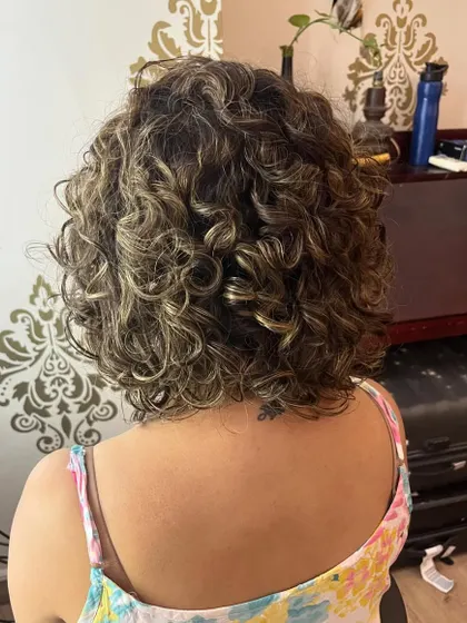 A curly bob with bangs and subtle highlights.