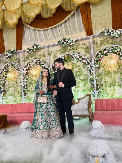 A candid moment between the couple on their reception stage, surrounded by a cloud of smoke from their grand entrance.