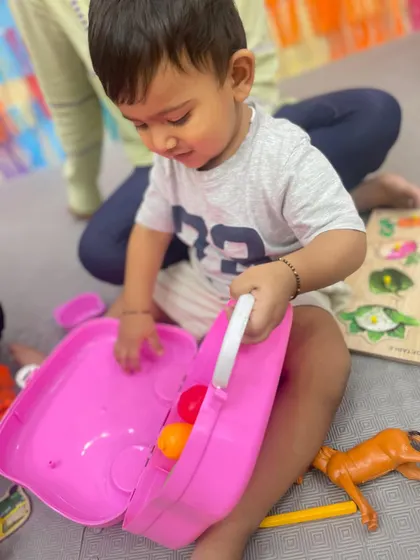 A toddler explores a toy basket during free play time, learning to make choices and engage with objects independently.