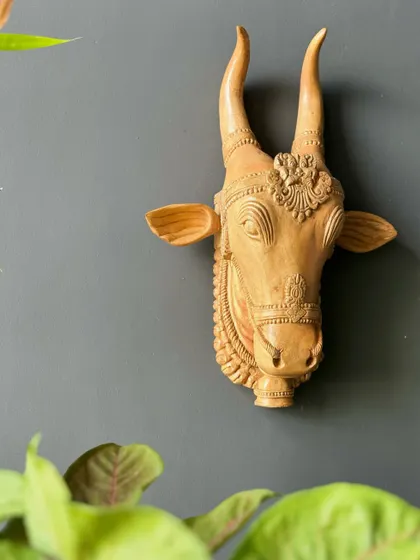 A hand-carved wooden bull head, shown against a neutral wall. This piece, with its fine details and natural finish, is a beautiful example of how I curate decor that is both peaceful and personal.