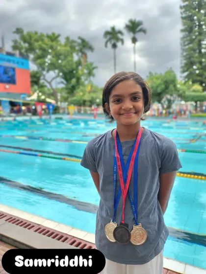 Samriddhi proudly wearing her medals by the pool.