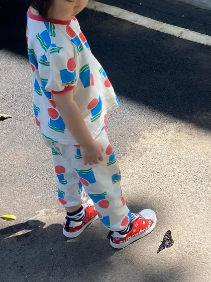 On one of our daily nature walks, a child stops to observe a butterfly on the pavement, a perfect moment of spontaneous learning.
