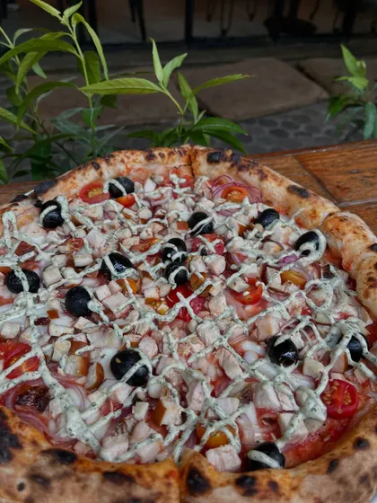 Another look at our smoked chicken pizza, topped with olives and a creamy drizzle.