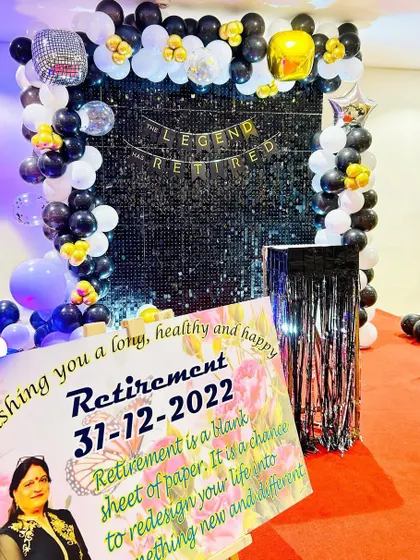 A retirement party decoration with a black shimmer wall and a personalized welcome sign. The banner reads "The Legend Has Retired".
