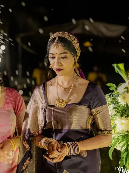 A candid moment from a traditional Coorgi ceremony. The bride's makeup is soft and elegant, with a focus on her eyes.