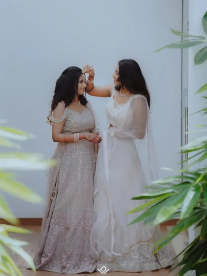 A sweet moment of friendship as a woman helps another with her hair or jewelry.