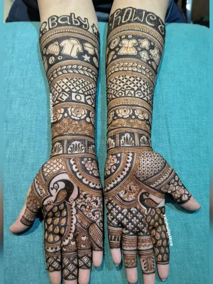 A full-coverage baby shower design. This intricate mehndi includes peacocks and traditional patterns, with "Baby Shower" written in a fun font on the arms.