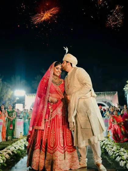 A perfect end to the ceremony. The groom kisses his bride on the forehead as fireworks go off in the background.