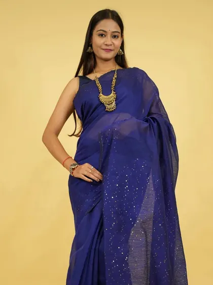 A model wears a long, traditional gold-toned necklace over a simple blue saree. This demonstrates how a single piece of statement jewellery can transform a simple outfit.