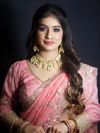 A soft and elegant look in a pink saree. The makeup features a beautiful purple smokey eye and a neutral lip, perfect for a wedding guest or bridesmaid.