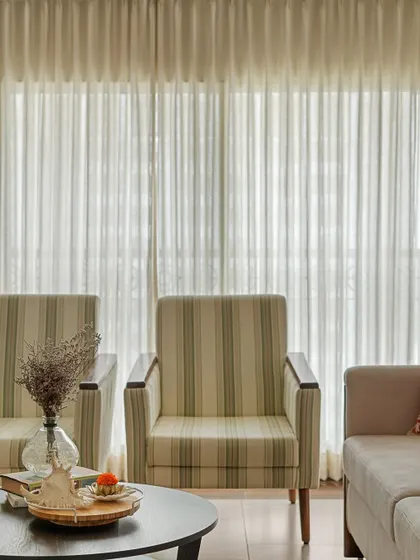 We focus on creating warm and calming living spaces. Here, the striped armchairs and sheer curtains filter natural light beautifully, making it the perfect place to unwind.