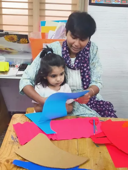 An instructor provides guidance to a very young student on her paper craft. We make sure every child, no matter their age, gets the support they need to create.