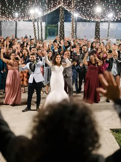 The entire wedding party joins in for a group dance. This wide shot captures the collective joy and energy of the celebration, with the couple at the center of it all.